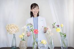 色と腸の専門サロンhaHa*の松山友美が、花に囲まれて微笑むプロフィール写真