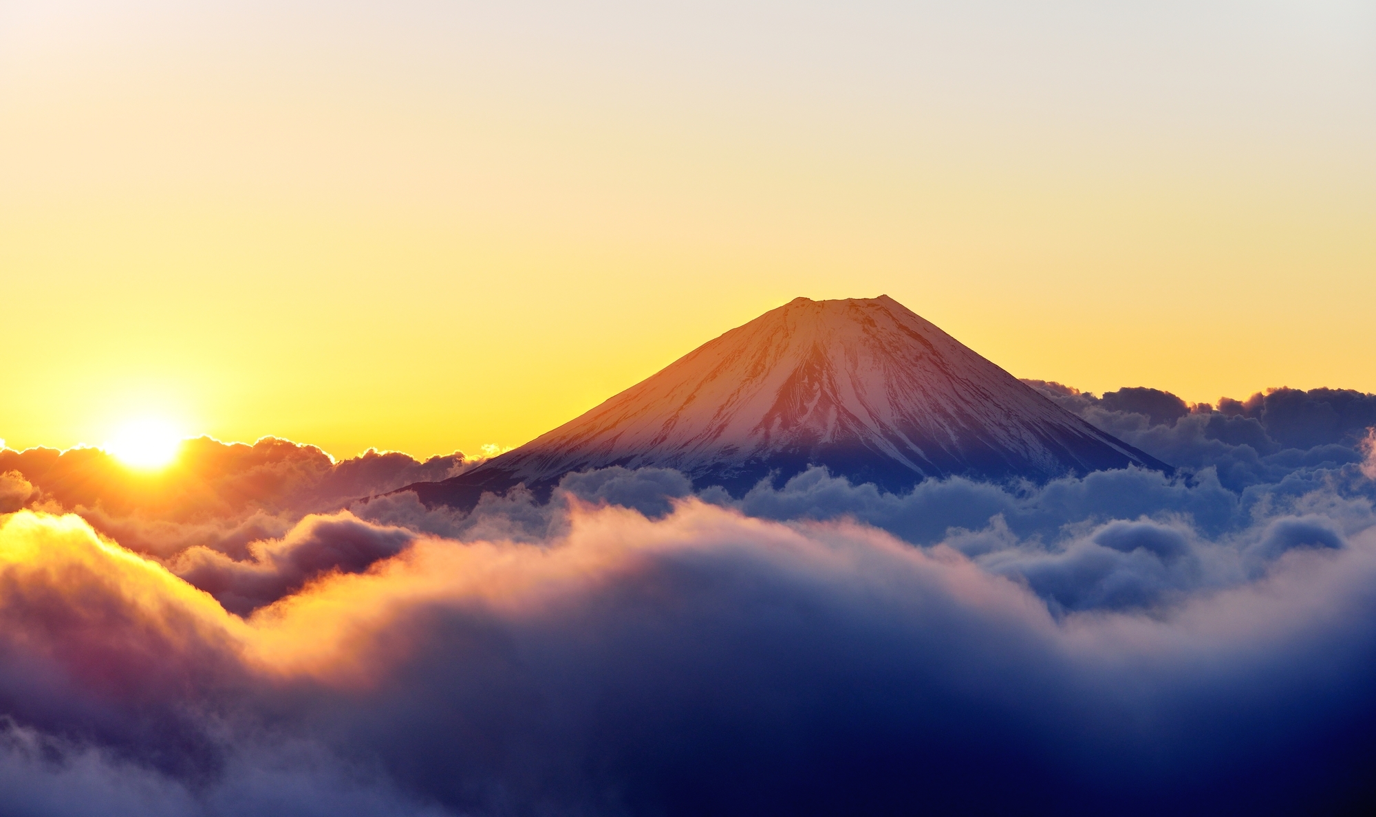 雲の上にそびえて陽光に輝く富士山