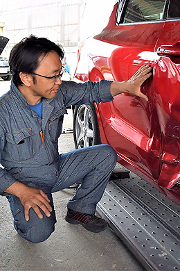 へこんだ車の様子を見る稲田さん