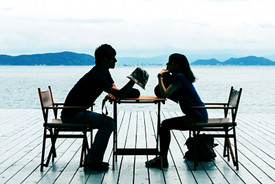 海辺のテラスで談話するカップル