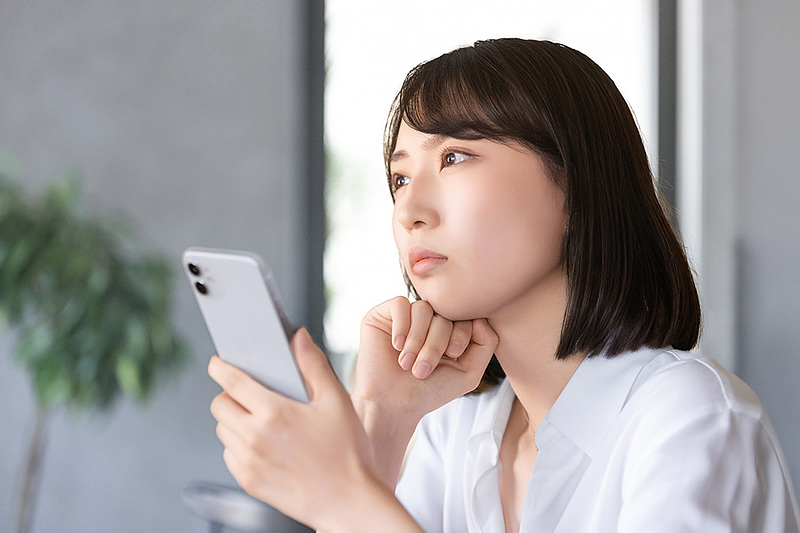 スマホを見て考える女性