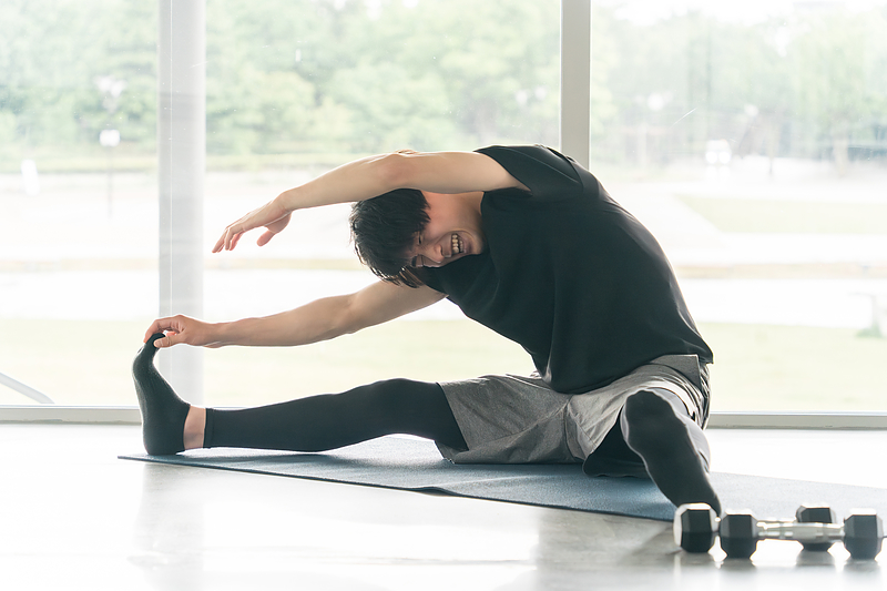 体が硬い男性がストレッチをしている画像